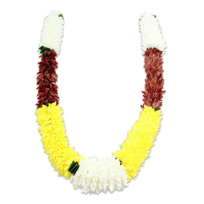 Framed against a plain white surface with a soft shadow beneath, this U-shaped floral garland reads as both ceremonial object and handcrafted textile. Each arm begins with a dense, cylindrical cluster of soft, creamy-white blossoms - miniature chrysanthemum-like forms whose packed fabric petals create a fluffy, cloud-like texture. Beneath those, a tight band of maroon or reddish-brown petals introduces a grounded, solemn tone, before the composition opens into a long, exuberant run of bright yellow flowers that form the broad, graceful curve of the 'U'. At the lowest point the two yellow sweeps converge in a larger, lush white cluster that serves as a luminous focal point; small, dark green leaf accents are used sparingly at the joins between colours to highlight transitions and add natural contrast. The photograph's soft, even lighting reveals the craftsmanship: thousands of individual fabric petals and tiny stitches arranged to mimic natural bloom density, producing a durable mala suitable for repeated ceremonial use. This style of garland is traditionally reserved for Hindu pooja, temple offerings, Indian weddings and festivals such as Diwali and Holi, where the white, yellow and maroon combination symbolizes purity, prosperity and devotion. As prepared by a Collier Row florist familiar with local families and community temples, the piece reads as respectful, substantial and ready for ritual display or home celebration in Romford, Noak Hill or nearby neighbourhoods.